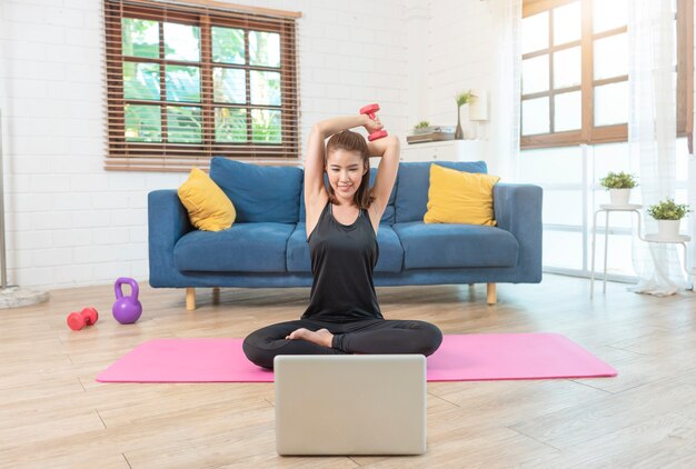 Jonge Aziatische gezonde vrouw in sportkleding training thuis, oefenen, passen, yoga doen. thuis sport fitness concept