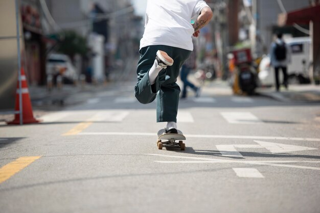 Jonge Aziatische man skateboarden in de stad buiten
