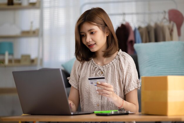 Jonge Aziatische vrouw die creditcard gebruikt om op de website te winkelen via een laptopcomputer Online winkelen en eCommerce-concept