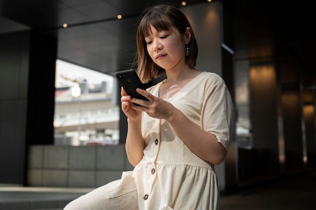 Jonge Aziatische vrouw die haar telefoon controleert