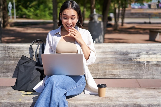 Gratis foto jonge aziatische vrouw die op videochat praat met laptop zittend op bank met online conferentie over rem