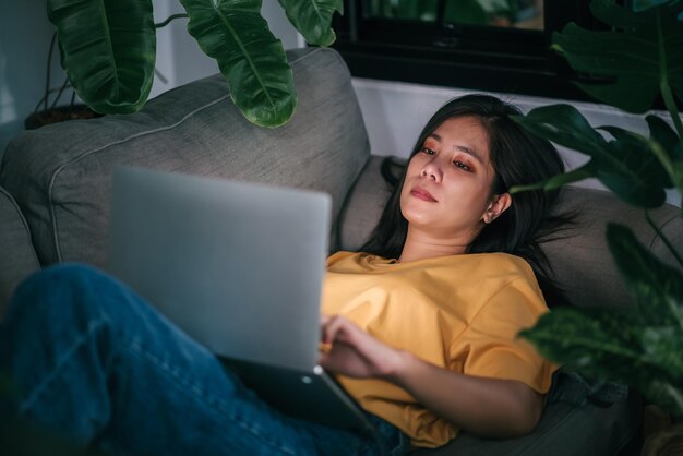 Jonge aziatische vrouw freelancer die 's nachts in de woonkamer werkt terwijl hij thuis werkt, geestelijke gezondheidszorg concept