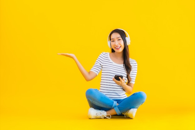 Jonge aziatische vrouw gebruik slimme mobiele telefoon met hoofdtelefoon