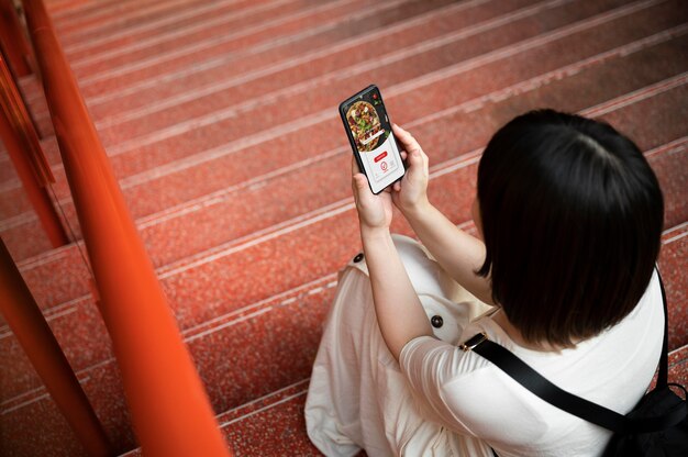 Jonge Aziatische vrouw kijkt naar een app op haar telefoon