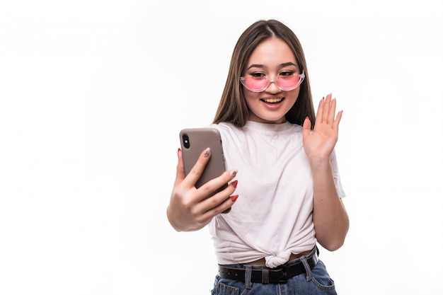 Jonge Aziatische vrouw met behulp van haar mobiele telefoon, geïsoleerd op een witte muur