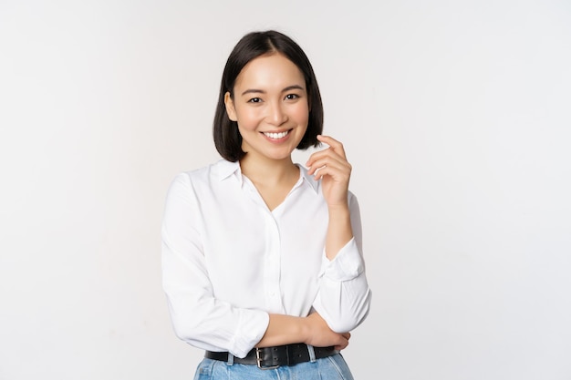 Jonge aziatische vrouw, professionele ondernemer die in kantoorkleding staat en glimlacht en er zelfverzekerd uitziet op een witte achtergrond