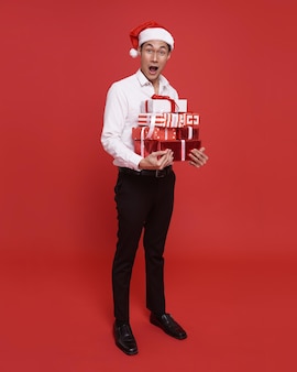 Jonge aziatische zakenman die een kerstmuts draagt en een geschenkdoos vasthoudt in kerstmis en een gelukkig nieuwjaarsfeest