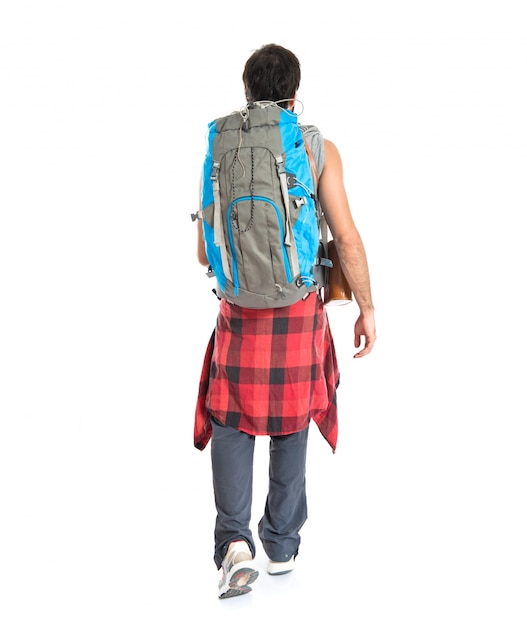 Jonge backpacker die over witte achtergrond loopt