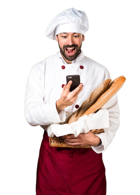 Jonge bakker met wat brood en praten met mobiel