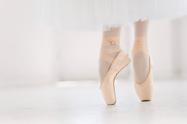 Jonge ballerina, close-up op benen en schoenen, staande in pointe-positie.