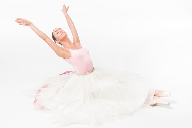 Gratis foto jonge ballerina danser met gesloten ogen ontspannen op witte achtergrond