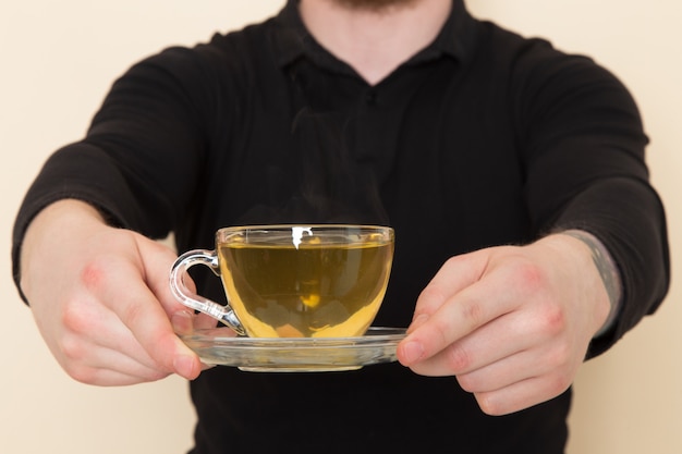 Gratis foto jonge barista in zwart pak met hete groene thee beker