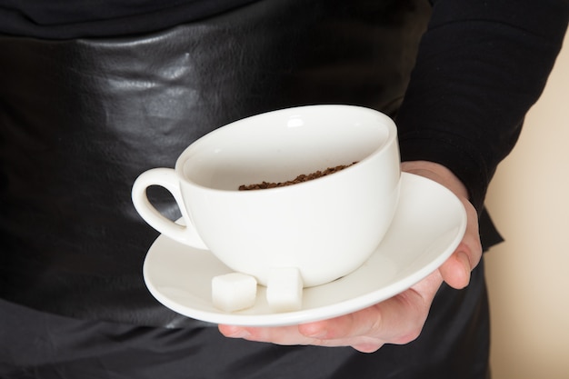 jonge barista in zwart pak met ingrediënten en koffie-apparatuur bruine koffie zaden op wit