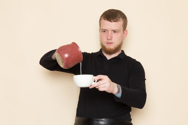 jonge barista in zwart pak met ingrediënten en koffie-apparatuur bruine koffie zaden op wit
