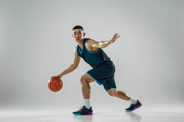 Jonge basketbalspeler van team dragen sportkleding training, oefenen in actie, beweging in run geïsoleerd op een witte muur. Concept van sport, beweging, energie en dynamische, gezonde levensstijl.