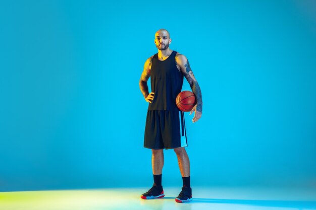 Jonge basketbalspeler van team dragen sportkleding training, oefenen in actie, beweging op blauwe muur in neonlicht