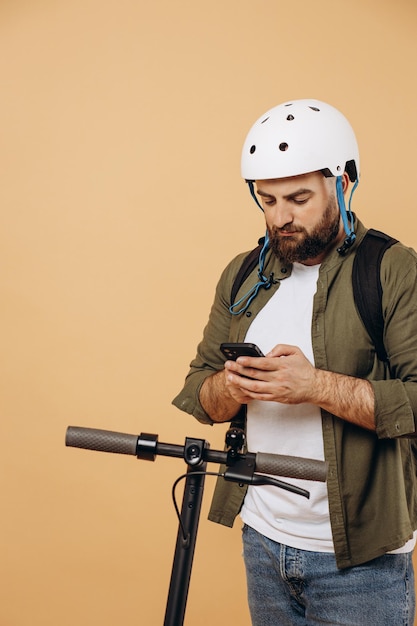 Jonge, bebaarde man die op een elektrische scooter rijdt en telefoon gebruikt