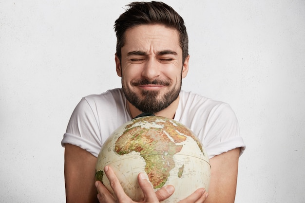 Gratis foto jonge, bebaarde man met globe