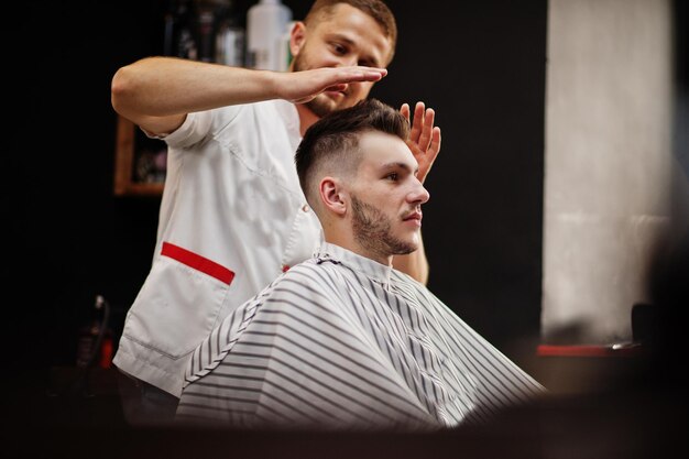 Jonge, bebaarde man wordt geknipt door kapper terwijl hij in een stoel zit bij kapperszaak Barber soul