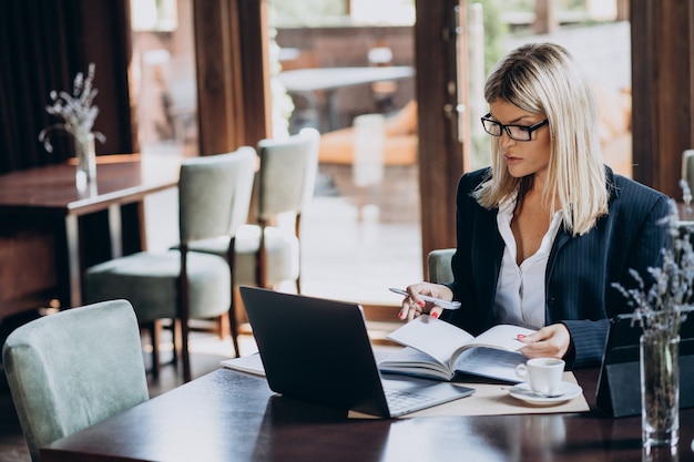 Jonge bedrijfsvrouw die aan computer in een koffie werkt