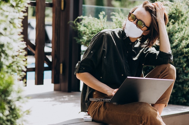 Jonge bedrijfsvrouw die aan computer van huis in masker werkt