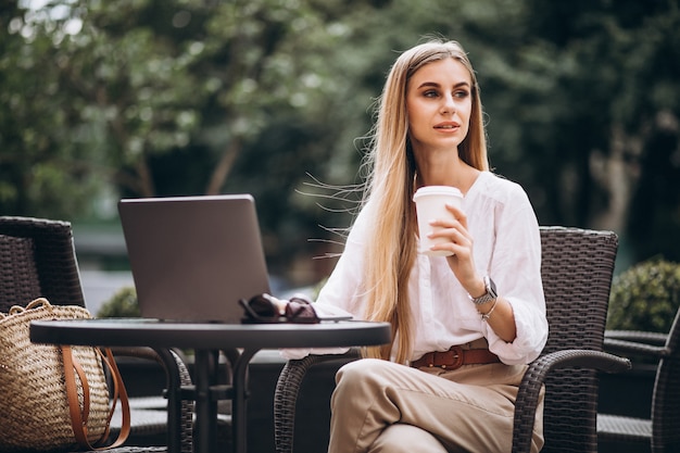 Jonge bedrijfsvrouw die aan laptop buiten in een koffie werkt