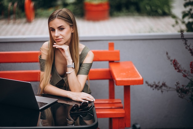 Jonge bedrijfsvrouw die aan laptop buiten in een koffie werkt