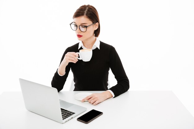 Jonge bedrijfsvrouw die glazen draagt die laptop computer met behulp van