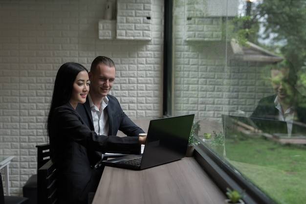 Jonge bedrijfsvrouw die iets toont om zakenman die op haar laptop wordt gezien te rijpen