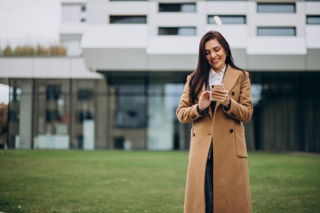 Jonge bedrijfsvrouw die telefoon met behulp van