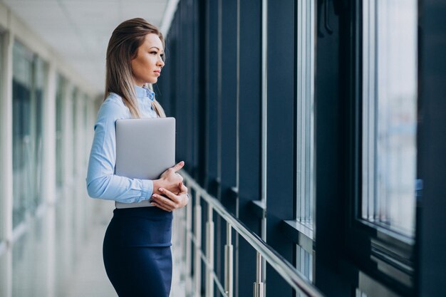 Jonge bedrijfsvrouw met laptop die zich in een bureau bevindt