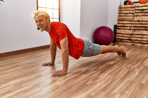 Jonge blanke man die lacht zelfverzekerde training in het sportcentrum