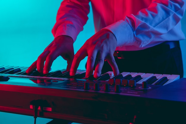 Jonge blanke muzikant, toetsenist spelen op verloop ruimte in neonlicht. Concept van muziek, hobby, festival