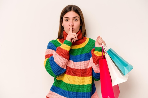 Jonge blanke vrouw die gaat winkelen geïsoleerd op een witte achtergrond die een geheim houdt of om stilte vraagt Premium Foto
