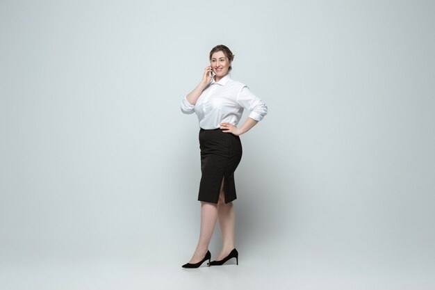 Jonge blanke vrouw in vrijetijdskleding op grijs. Lichaamspositief vrouwelijk karakter, plus size