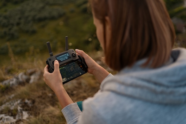 Jonge blanke vrouw navigeren een vliegende drone met afstandsbediening