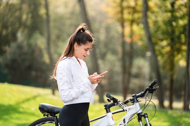 Jonge blanke vrouw rusten in een park, maakt gebruik van een mobiele telefoon.