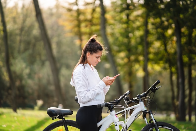 Jonge blanke vrouw rusten in een park, maakt gebruik van een mobiele telefoon.