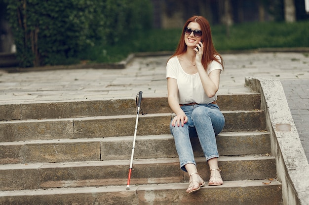 Gratis foto jonge blinde met lange stok wandelen in een stad