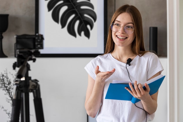 Gratis foto jonge bloggeropname met professionele camera die een boek houdt