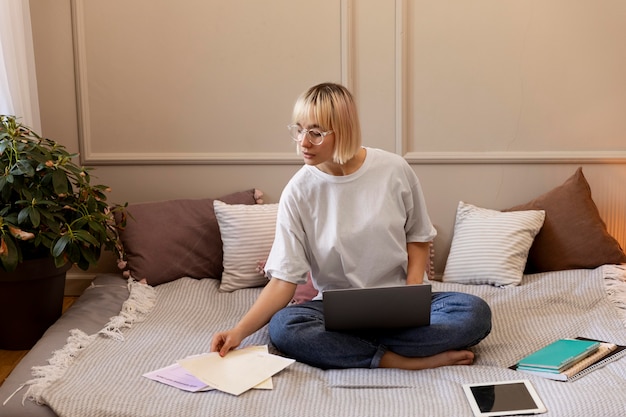 Jonge blonde vrouw die thuis op haar laptop werkt
