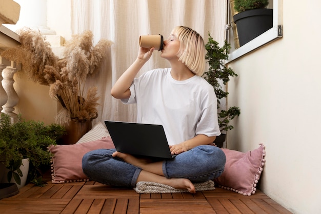 Gratis foto jonge blonde vrouw die vanuit huis op de vloer werkt