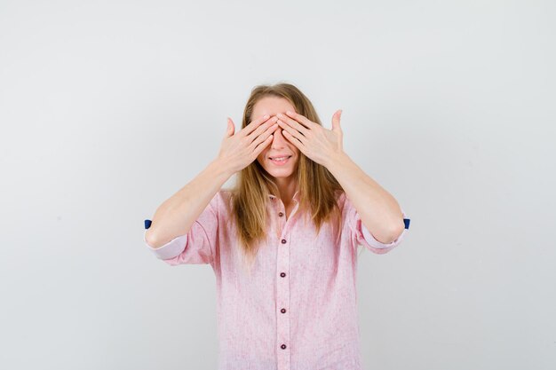 Jonge blonde vrouw in een casual roze shirt dat haar ogen bedekt