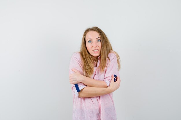 Jonge blonde vrouw in een casual roze shirt ijskoud