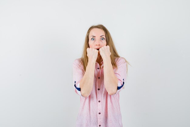 Jonge blonde vrouw in een casual roze shirt met vuisten