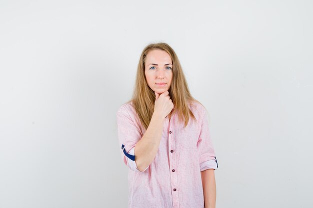 Jonge blonde vrouw in een casual roze shirt