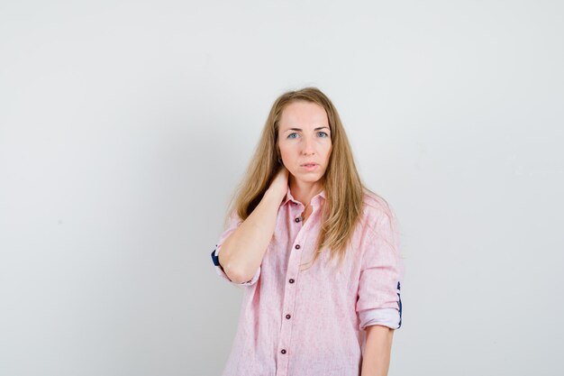 Jonge blonde vrouw in een casual roze shirt