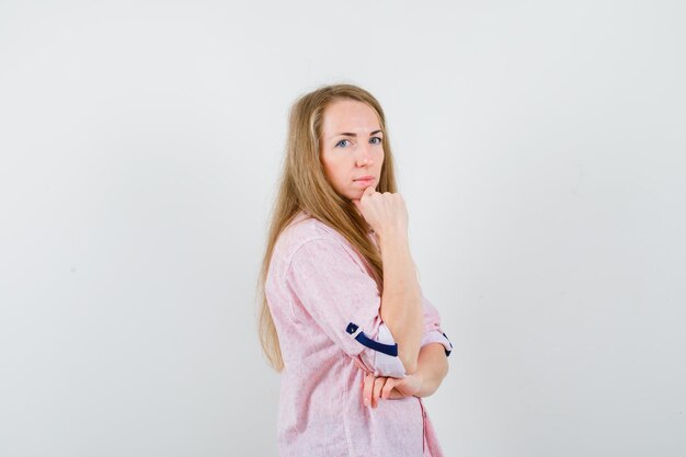 Jonge blonde vrouw in een casual roze shirt