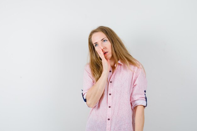 Jonge blonde vrouw in een casual roze shirt