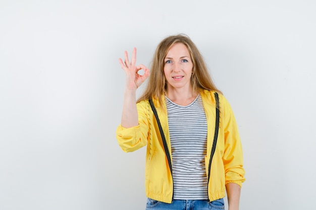 Jonge blonde vrouw in een geel jasje